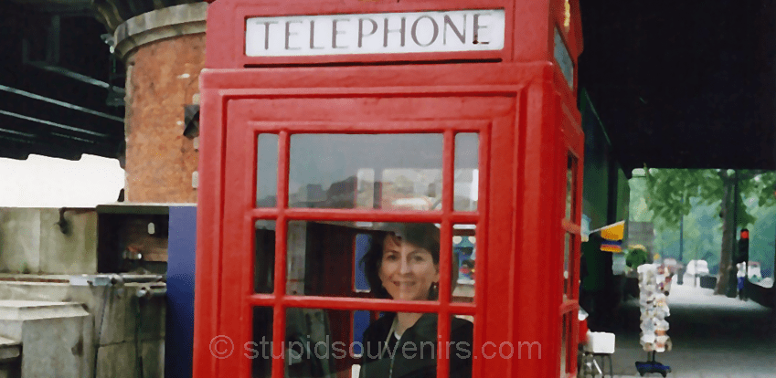tourist posing in one of London's red phone booths.